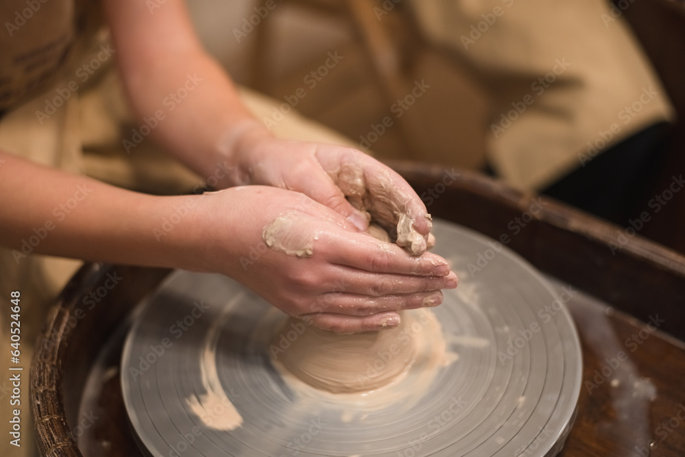 Potter girl works on potter's wheel, making ceramic pot out of clay in pottery workshop Potter girl works on potter's wheel, making ceramic pot out of clay in pottery workshop