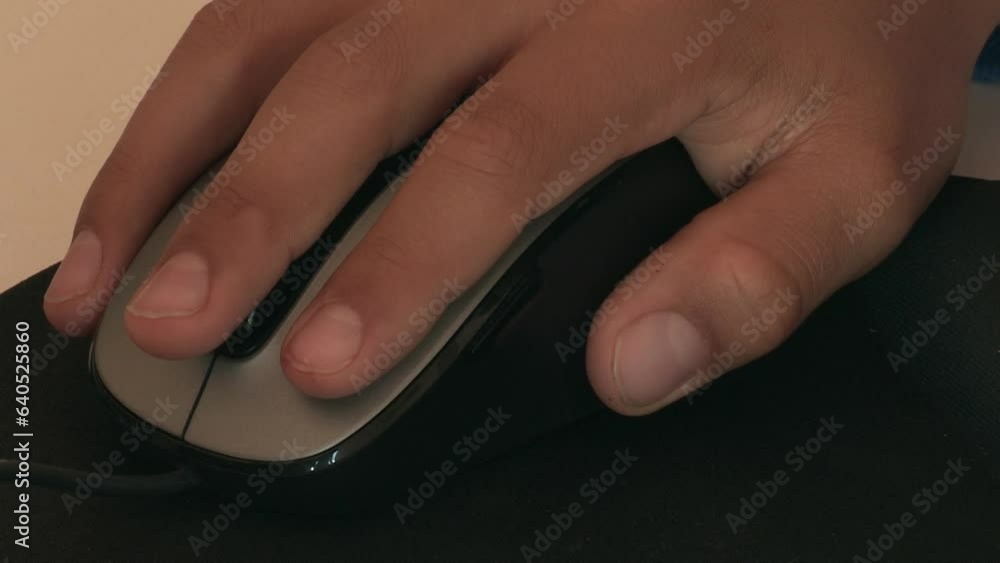 Child's hand moving a computer mouse on top of a black mouse pad. Child's hand moving a computer mouse on top of a black mouse pad.