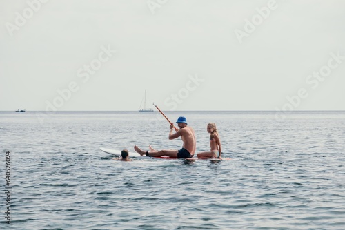 Family sea sup. Young happy father with his son and daughter Floating on a SUP board, paddling in blue sea water. summer vacation and Dad and Son Daughter concept.