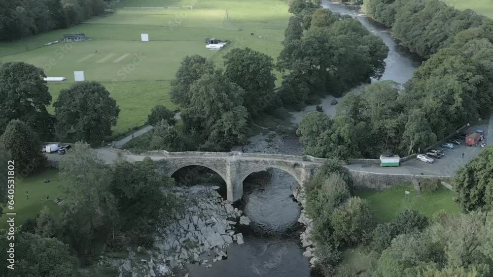 An aerial view of the Devil's Bridge at Kirkby Lonsdale on a summer evening, Yorkshire, England, UK. Flying right to left around the southerly side of the bridge while zooming out. An aerial view of the Devil's Bridge at Kirkby Lonsdale on a summer evening, Yorkshire, England, UK. Flying right to left around the southerly side of the bridge while zooming out.