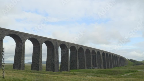 Viaduct bridge over moorland on windy overcast summer afternoon with passing train at Ribblehead Viaduct, Yorkshire, UK. Time lapse 30x.