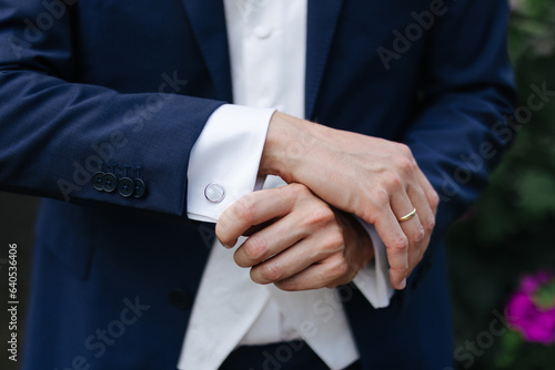 Groom showing his cufflinks and hands close-up