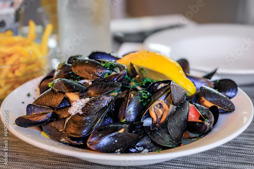 Freshly cooked mussels steamed in white wine sauce or moules marinieres on a plate at a restaurant in Menton Old Town, French Riviera, South of France