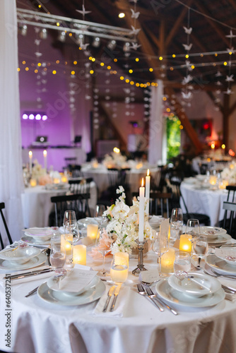Beautiful table setting and decorations at a wedding. Wedding venue with beautiful decor, flowers, cutlery and lights