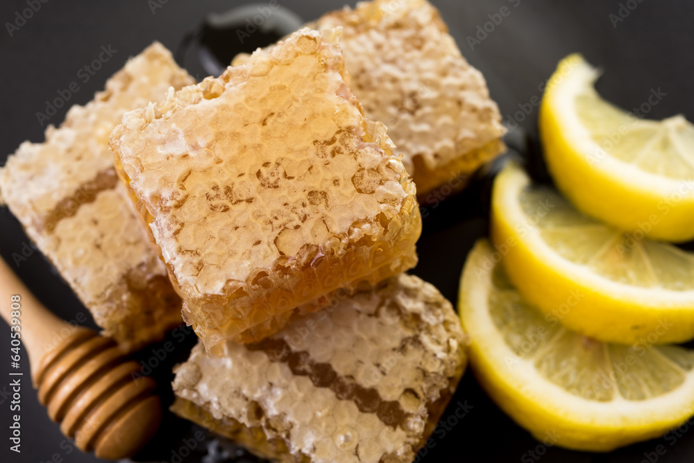 honeycomb and honey with fresh lemon on black background