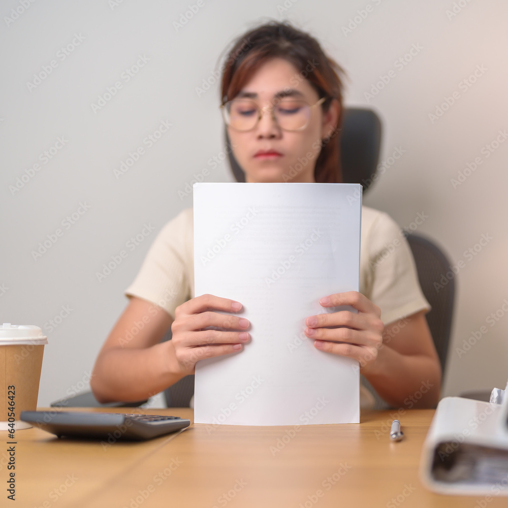 Asian woman working hard with financial report folder, female businesswoman sign contract or reading documents paper at home or office late night. Overworked, work hard and business concept Asian woman working hard with financial report folder, female businesswoman sign contract or reading documents paper at home or office late night. Overworked, work hard and business concept