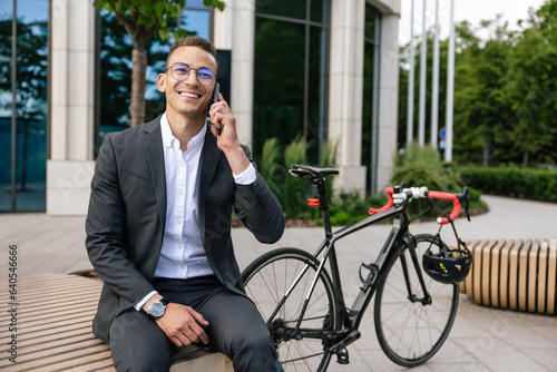 Young man in elegant suit talking on the phone and looking contented photo