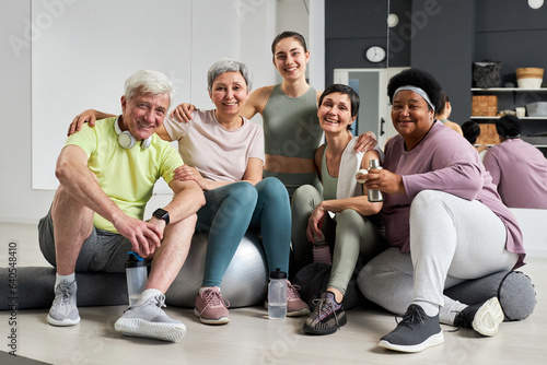 Portrait of fitness instructor smiling at camera with her group in health studio