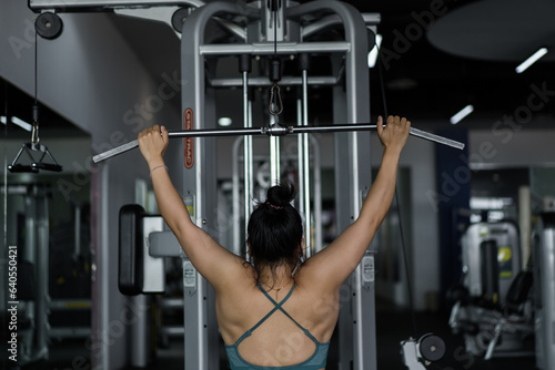 Fitness woman working out in gym doing exercise for back. Athletic girl doing lat pulldown