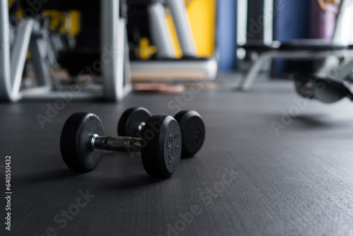 woman doing stretching exercises on the floor and dumbbell in the foreground