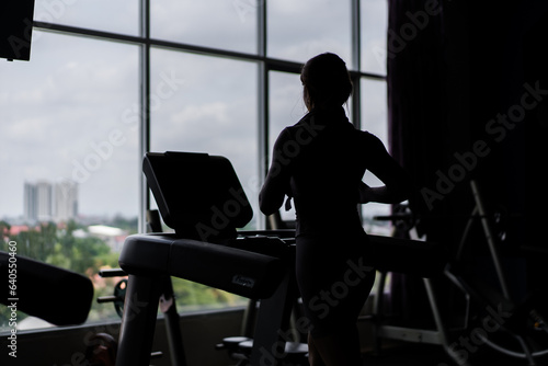 Young woman training in fitness club, gym and sport activity. Female working out and running on treadmill. Health, sport and cardio workout concept