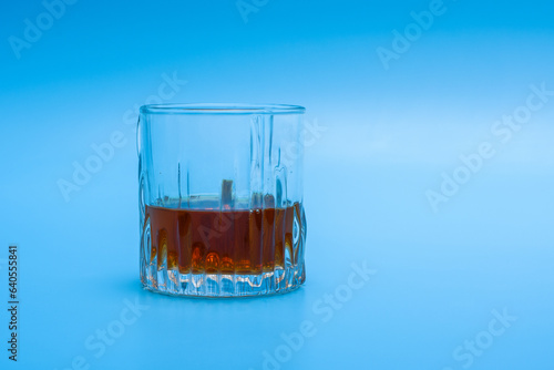 Izolowana szklanka do whisky z nalanym alkoholem na niebieskim tle