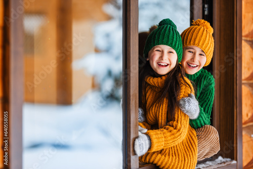 Hello winter holiday! Happy children play together outdoor in open window. Happy New Year and Merry Christmas family celebration!