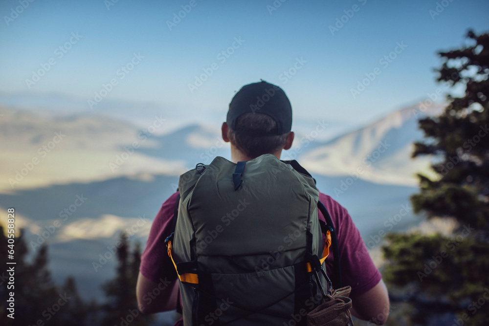 A male hiker pauses to enjoy the view on the mountain at sunrise. A male hiker pauses to enjoy the view on the mountain at sunrise.