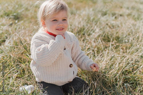 Cute baby blonde in a knitted sweater in the field photo