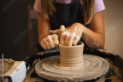 Close up of teenage girl's hands modeling pottery on a potter wh photo