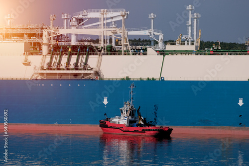 Tug boat alongside the LNG tanker during ship-to-ship gas transfer operation. Guard vessel and LNG carrier