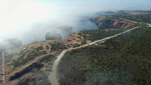 Flyover clouds of fog toward scenic Rocky coastline in Portugal Southeast