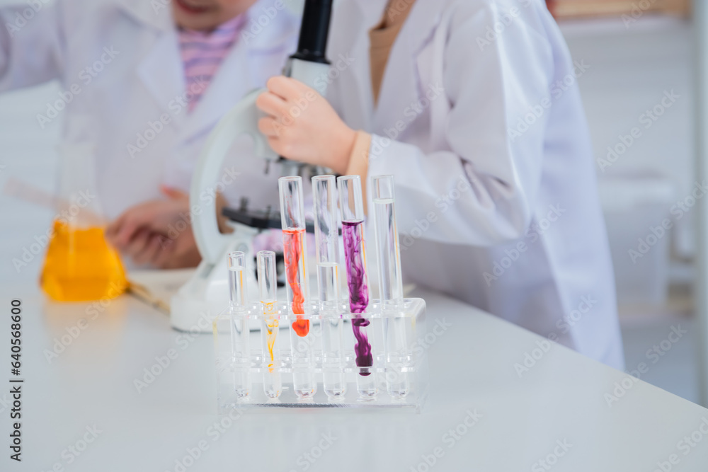 Fototapeta premium Unrecognizable close-up primary school boy student wearing lab coats happy studying with chemical teacher analyzing substance liquid test in laboratory room, lifestyle learning education science class