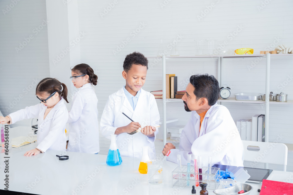 Cheerful group of Multicultural primary school students wearing lab coats studying with Indian teacher writing experiment test paperwork in laboratory room, lifestyle learning education science class Cheerful group of Multicultural primary school students wearing lab coats studying with Indian teacher writing experiment test paperwork in laboratory room, lifestyle learning education science class