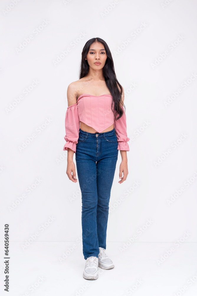 Front view of a slim asian trans woman. Wearing a light pink off-shoulder blouse, jeans and white sneakers. Whole body photo on a white background. Front view of a slim asian trans woman. Wearing a light pink off-shoulder blouse, jeans and white sneakers. Whole body photo on a white background.