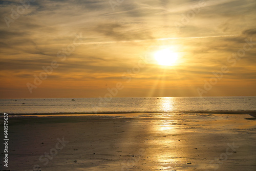 Sunset  illuminated sea. Sandy beach in the foreground. Light waves. Baltic Sea