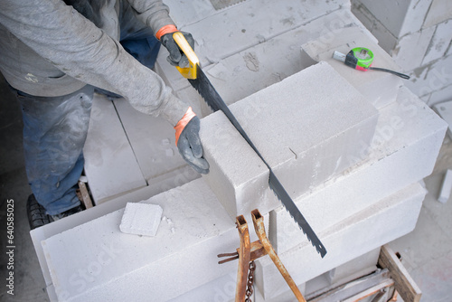 Builder sawing foam concrete for the construction of a new building