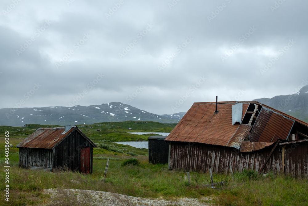 Norwegian Mountain Landscape with Damaged Building and Majestic Mountain in Scenic Nature of Haukelifjell by road E134. Norwegian Mountain Landscape with Damaged Building and Majestic Mountain in Scenic Nature of Haukelifjell by road E134.