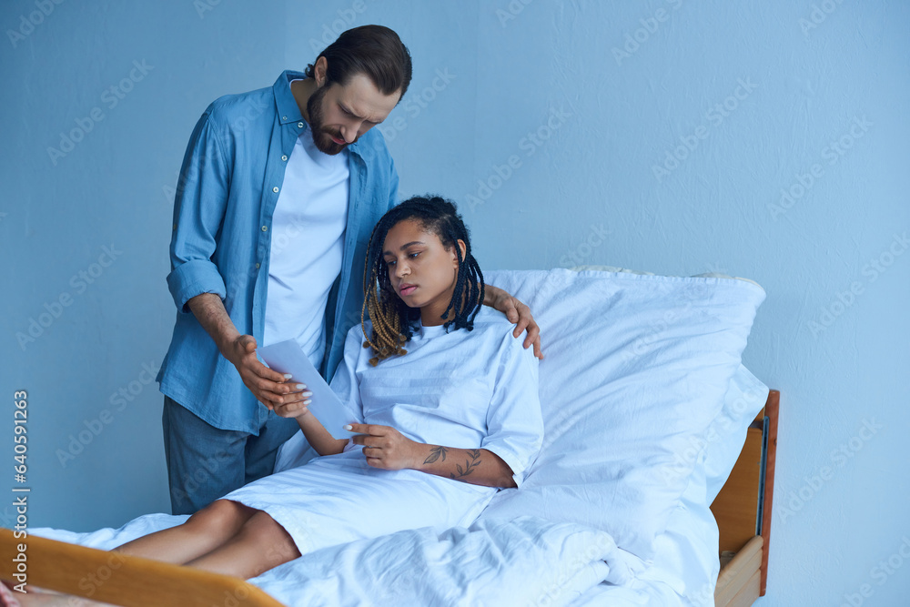 man standing near sad african american wife, looking at ultrasound, hospital, miscarriage concept man standing near sad african american wife, looking at ultrasound, hospital, miscarriage concept