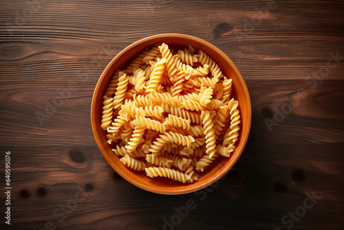 Top view of vegetarian pasta bowl with fusilli on wooden background