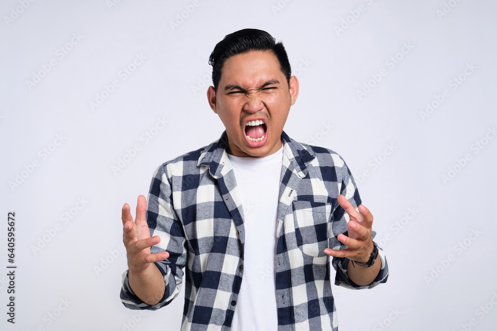 Annoyed young Asian man in casual shirt raising his hands with angry expression isolated on white background Annoyed young Asian man in casual shirt raising his hands with angry expression isolated on white background