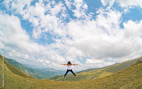 The path to success, challenges and dreams - concept. A young woman jumps up in a beautiful mountain landscape. 