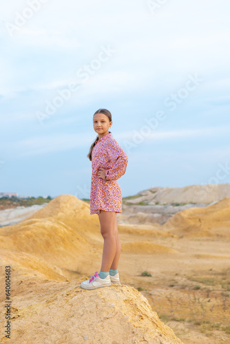 Girl walks clay mountains outside the city.