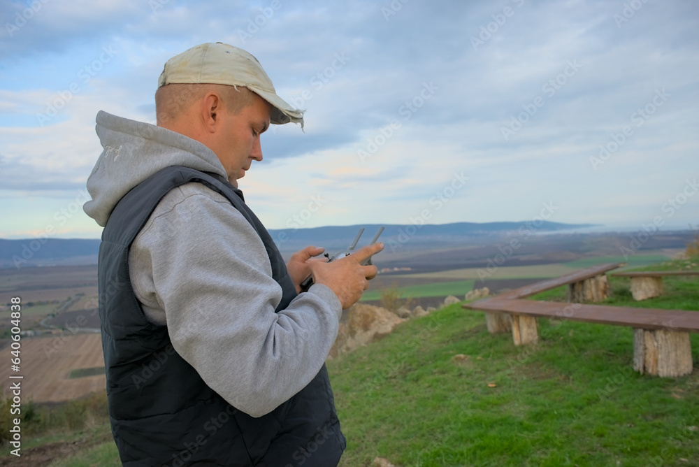 An operator with a remote control pilots an unmanned compact drone