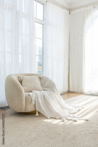 a soft white comfortable round armchair with a pillow in a gentle cozy bright apartment with huge panoramic windows with sunlight