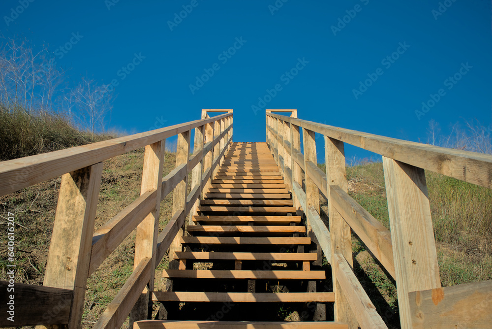 wooden staircase sharply going up into the blue sky