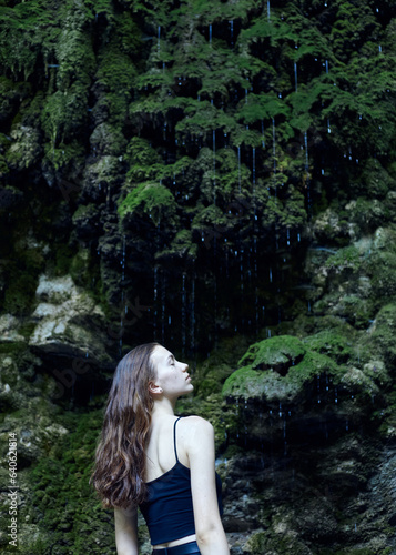 a beautiful woman on the background of a tropical forest with dripping drops of water, posing relaxed