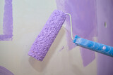 Using a paint roller to paint a concrete wall inside a house with water-based paint