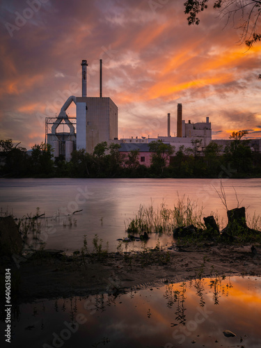 Dramatic sunset cloudscape over the Penobscot River in Bradley, north of Bangor, Maine, with the views of old factories and slanted trees in silhouette photo