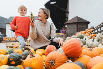 Mother and daughter choosing pumpkins at farm market at autumn season