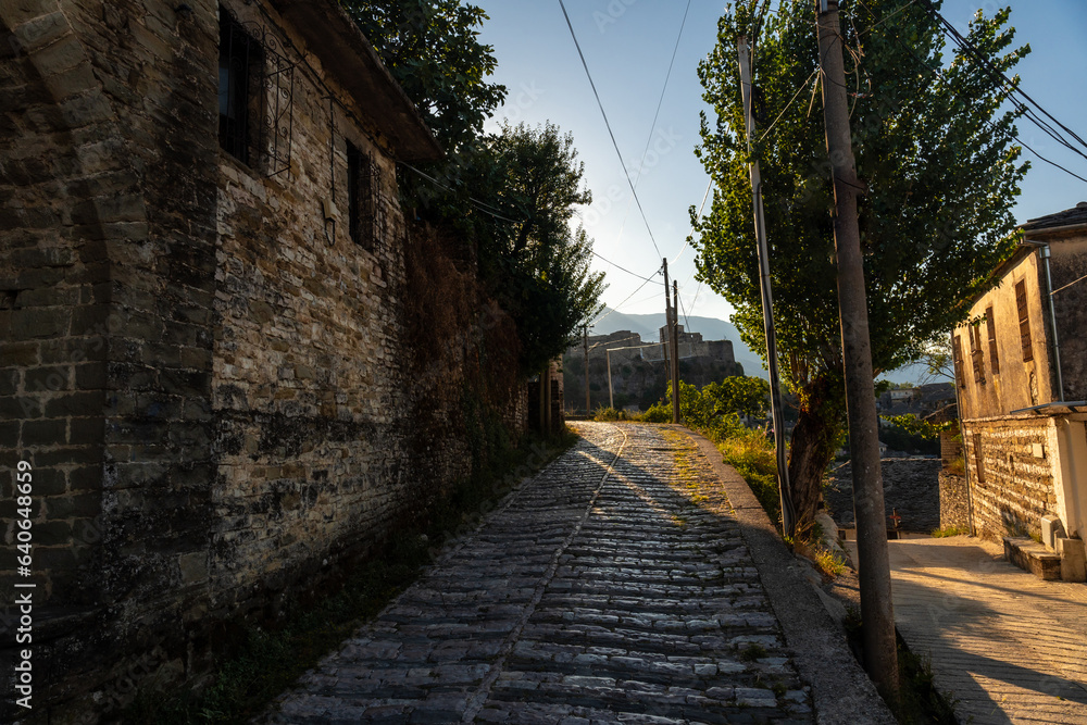 Rural road heading towards the Sunset over the clock tower and fortress of in the city of Gjirokaster, Albania Rural road heading towards the Sunset over the clock tower and fortress of in the city of Gjirokaster, Albania