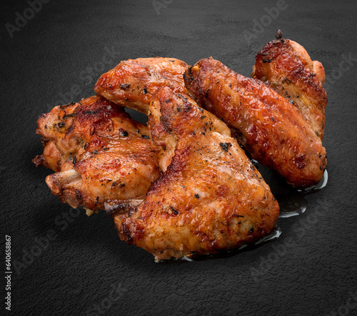 Grilled chicken wings on a dark stone background. BBQ menu photo