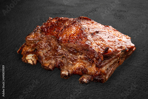 Grilled pork ribs, handmade on a dark stone background. BBQ menu