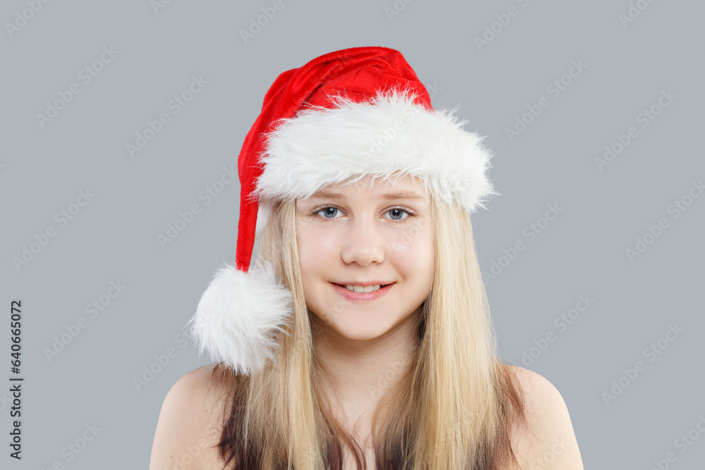 Christmas child girl in red Santa hat on gray background Christmas child girl in red Santa hat on gray background