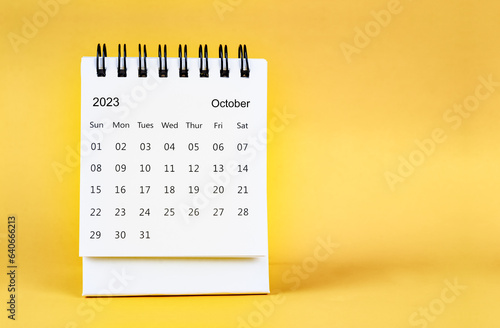 The October 2023 desk calendar on yellow color background.