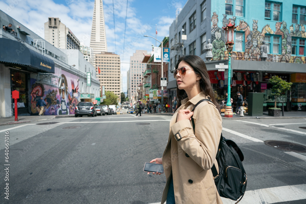 Fototapeta premium side view of asian Korean business woman wearing sunglasses passing by road intersection on her way to office in the financial district of san Francisco's Chinatown in California usa