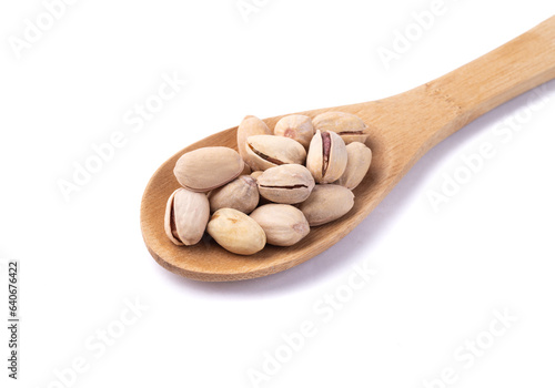 Salted roasted pistachios on a spoon isolated over white background