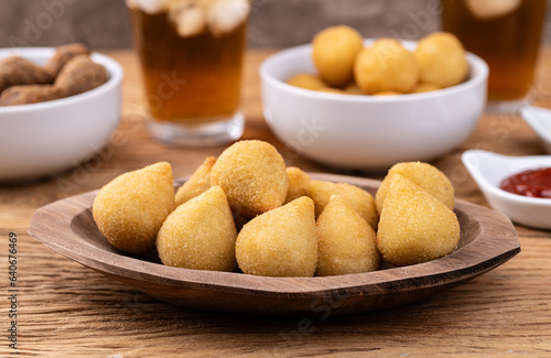Typical brazilian snack coxinha on a plate with soda glass, ketchup and mustard