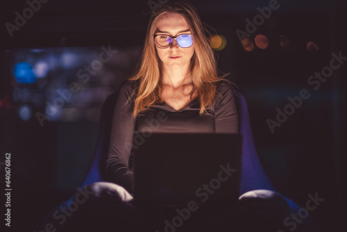 Laptop on woman's lap. A face illuminated by a laptop display. Work at night.