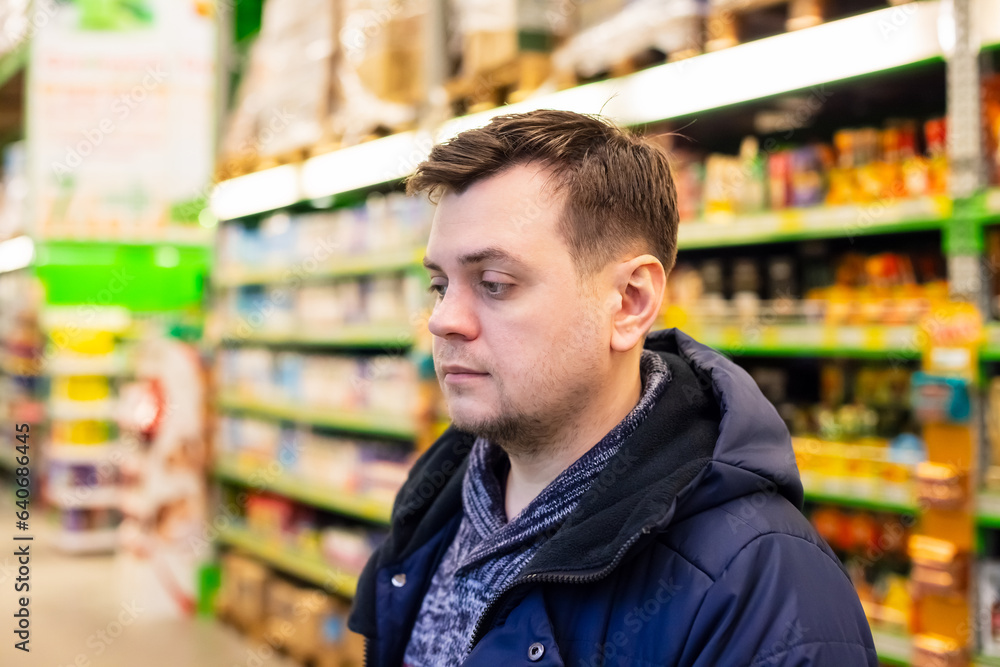 middle aged caucasian male man buying groceries in supermarket, grocery shop on store shelves background. consumerism concept. headshot view portrait